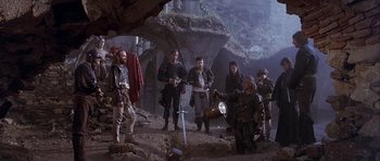 Movie still from “Flesh+Blood” (1985), directed by Paul Verhoeven – A group of people standing in a cave with a sword; Wide shot, High angle
