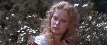Movie still from “Flesh+Blood” (1985), directed by Paul Verhoeven – A woman with blonde curly hair wearing a white shirt; Close Up shot, Over the shoulder angle