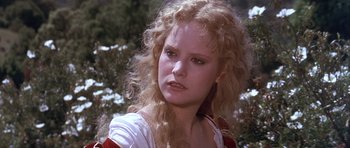 Movie still from “Flesh+Blood” (1985), directed by Paul Verhoeven – A woman with blonde curly hair wearing a white shirt; Close Up shot, Over the shoulder angle