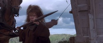 Movie still from “Flesh+Blood” (1985), directed by Paul Verhoeven – A woman is holding a bow and arrow in her hands; Medium shot, Low angle
