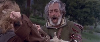 Movie still from “Flesh+Blood” (1985), directed by Paul Verhoeven – An old man with long white hair and a gray beard; Close Up shot, Over the shoulder angle