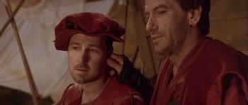 Movie still from “Flesh+Blood” (1985), directed by Paul Verhoeven – Two men in medieval garb , one of which has his hand on the ear of another man; Close Up shot, Over the shoulder angle