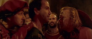 Movie still from “Flesh+Blood” (1985), directed by Paul Verhoeven – A group of men standing next to each other in a room; Close Up shot, Over the shoulder angle