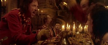 Movie still from “Flesh+Blood” (1985), directed by Paul Verhoeven – A group of people sitting around a table with candles; Close Up shot, Low angle