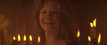 Movie still from “Flesh+Blood” (1985), directed by Paul Verhoeven – A woman smiles brightly while holding a lit candle; Close Up shot, Low angle