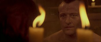 Movie still from “Flesh+Blood” (1985), directed by Paul Verhoeven – A man in a bath tub with a candle in front of him; Close Up shot, High angle