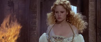Movie still from “Flesh+Blood” (1985), directed by Paul Verhoeven – A young woman with long blonde curly hair wearing a white dress; Close Up shot, High angle