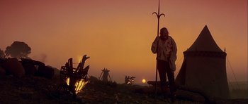 Movie still from “Flesh+Blood” (1985), directed by Paul Verhoeven – A man standing in a field at sunset with a spear; Wide shot, Low angle