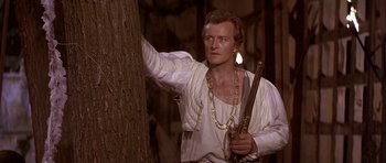 Movie still from “Flesh+Blood” (1985), directed by Paul Verhoeven – A man holding a sword in front of a tree; Medium shot, Over the shoulder angle