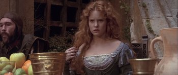 Movie still from “Flesh+Blood” (1985), directed by Paul Verhoeven – A beautiful young woman with long red hair and wearing a dress; Close Up shot, Over the shoulder angle