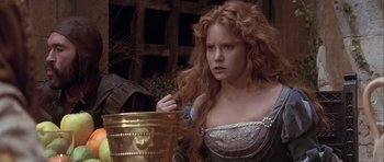 Movie still from “Flesh+Blood” (1985), directed by Paul Verhoeven – A woman with long red hair is looking at a gold container; Close Up shot, Over the shoulder angle