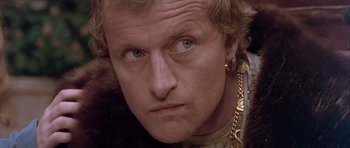 Movie still from “Flesh+Blood” (1985), directed by Paul Verhoeven – A person wearing a necklace; Close Up shot, Over the shoulder angle