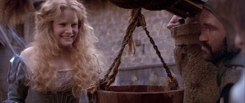 Movie still from “Flesh+Blood” (1985), directed by Paul Verhoeven – A woman with long blonde curly hair standing next to a wooden bucket; Close Up shot, Low angle