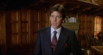 Movie still from “Fletch” (1985), directed by Michael Ritchie – A man wearing a suit and tie in a room; Close Up shot, Low angle