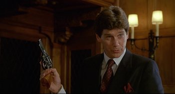 Movie still from “Fletch” (1985), directed by Michael Ritchie – A person holding a gun; Close Up shot, Low angle