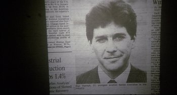 Movie still from “Fletch” (1985), directed by Michael Ritchie – A newspaper article with a picture of a man in a business suit; Extreme Close Up shot, Overhead angle