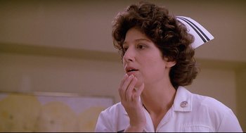 Movie still from “Fletch” (1985), directed by Michael Ritchie – A woman with curly brown hair is sitting in a room; Close Up shot, Low angle