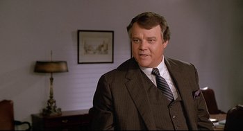 Movie still from “Fletch” (1985), directed by Michael Ritchie – A person wearing a suit and tie; Close Up shot, Over the shoulder angle