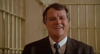 Movie still from “Fletch” (1985), directed by Michael Ritchie – A person wearing a suit and tie; Close Up shot, Low angle