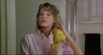 Movie still from “Fletch” (1985), directed by Michael Ritchie – A young woman is holding a hair dryer in her hand; Close Up shot, Low angle