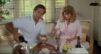 Movie still from “Fletch” (1985), directed by Michael Ritchie – A man and a woman sitting at a table with wine glasses; Medium shot, High angle