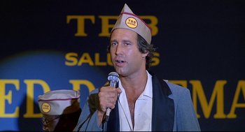 Movie still from “Fletch” (1985), directed by Michael Ritchie – A man wearing a hat is holding a microphone; Close Up shot, Low angle