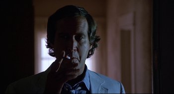 Movie still from “Fletch” (1985), directed by Michael Ritchie – A man smoking a cigarette while wearing a suit; Close Up shot, Low angle
