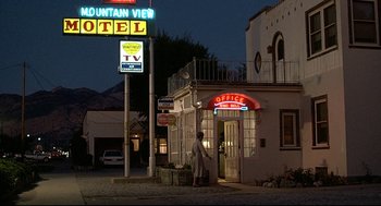 Movie still from “Fletch” (1985), directed by Michael Ritchie – A man standing in front of a hotel at night; Extreme Wide shot, Low angle