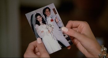 Movie still from “Fletch” (1985), directed by Michael Ritchie – A woman holding a picture of a newly married couple; Close Up shot, High angle