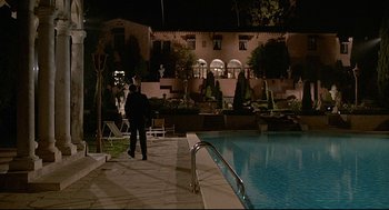 Movie still from “Fletch” (1985), directed by Michael Ritchie – A man standing next to a swimming pool at night; Extreme Wide shot, Low angle