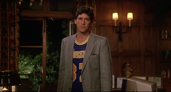 Movie still from “Fletch” (1985), directed by Michael Ritchie – A man wearing a lakers shirt and a jacket; Medium shot, Low angle