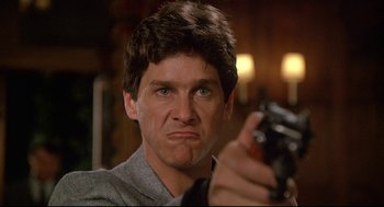 Movie still from “Fletch” (1985), directed by Michael Ritchie – A person holding a gun; Close Up shot, Low angle