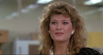 Movie still from “Fletch” (1985), directed by Michael Ritchie – A person wearing a suit and tie; Close Up shot, Over the shoulder angle