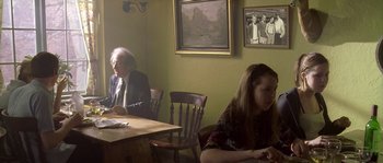 Movie still from “Flickering Lights” (2000), directed by Anders Thomas Jensen – A man and a woman sitting at a dining room table; Medium shot, Over the shoulder angle