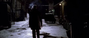 Movie still from “Flickering Lights” (2000), directed by Anders Thomas Jensen – A man walking down a street at night with smoke coming out of his mouth; Wide shot, Low angle