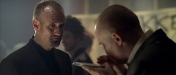 Movie still from “Flickering Lights” (2000), directed by Anders Thomas Jensen – A man looking at another man holding a cell phone; Close Up shot, Over the shoulder angle