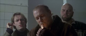 Movie still from “Flickering Lights” (2000), directed by Anders Thomas Jensen – A man lighting a cigarette in a dark room; Close Up shot, Over the shoulder angle