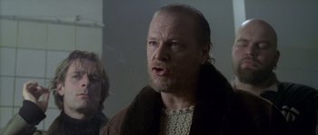 Movie still from “Flickering Lights” (2000), directed by Anders Thomas Jensen – A man with a beard and a sweater on; Close Up shot, Over the shoulder angle