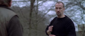 Movie still from “Flickering Lights” (2000), directed by Anders Thomas Jensen – A man in a black sweater holding a knife in his hand; Close Up shot, Low angle