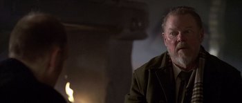 Movie still from “Flickering Lights” (2000), directed by Anders Thomas Jensen – An older man sitting in front of a fireplace; Close Up shot, Over the shoulder angle