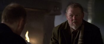 Movie still from “Flickering Lights” (2000), directed by Anders Thomas Jensen – An older man with a goatee and beard wearing a coat; Close Up shot, Low angle