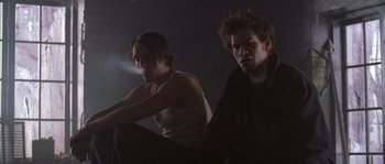 Movie still from “Flickering Lights” (2000), directed by Anders Thomas Jensen – Two young men sitting in a dimly - lit room; Medium shot, Low angle