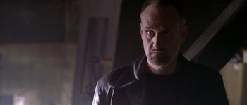 Movie still from “Flickering Lights” (2000), directed by Anders Thomas Jensen – A man in a black leather jacket looking at the camera; Close Up shot, Low angle