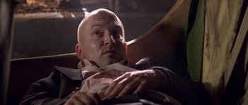 Movie still from “Flickering Lights” (2000), directed by Anders Thomas Jensen – A bald man sitting in a chair with his head resting on a pillow; Close Up shot, Low angle