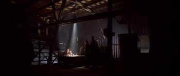 Movie still from “Flickering Lights” (2000), directed by Anders Thomas Jensen – A group of people sitting at a table in a dark room; Wide shot, Low angle