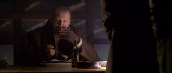 Movie still from “Flickering Lights” (2000), directed by Anders Thomas Jensen – A man sitting at a table with a bottle of wine; Medium shot, High angle