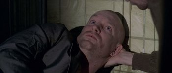 Movie still from “Flickering Lights” (2000), directed by Anders Thomas Jensen – A man with a shaved head is laying down; Close Up shot, Low angle
