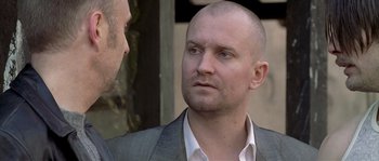 Movie still from “Flickering Lights” (2000), directed by Anders Thomas Jensen – A man in a suit and tie talking to another man in a suit and tie; Close Up shot, Over the shoulder angle