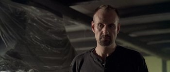 Movie still from “Flickering Lights” (2000), directed by Anders Thomas Jensen – A person wearing a black shirt; Close Up shot, Low angle