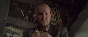 Movie still from “Flickering Lights” (2000), directed by Anders Thomas Jensen – A bald man holding a screwdriver in his hand; Close Up shot, Low angle
